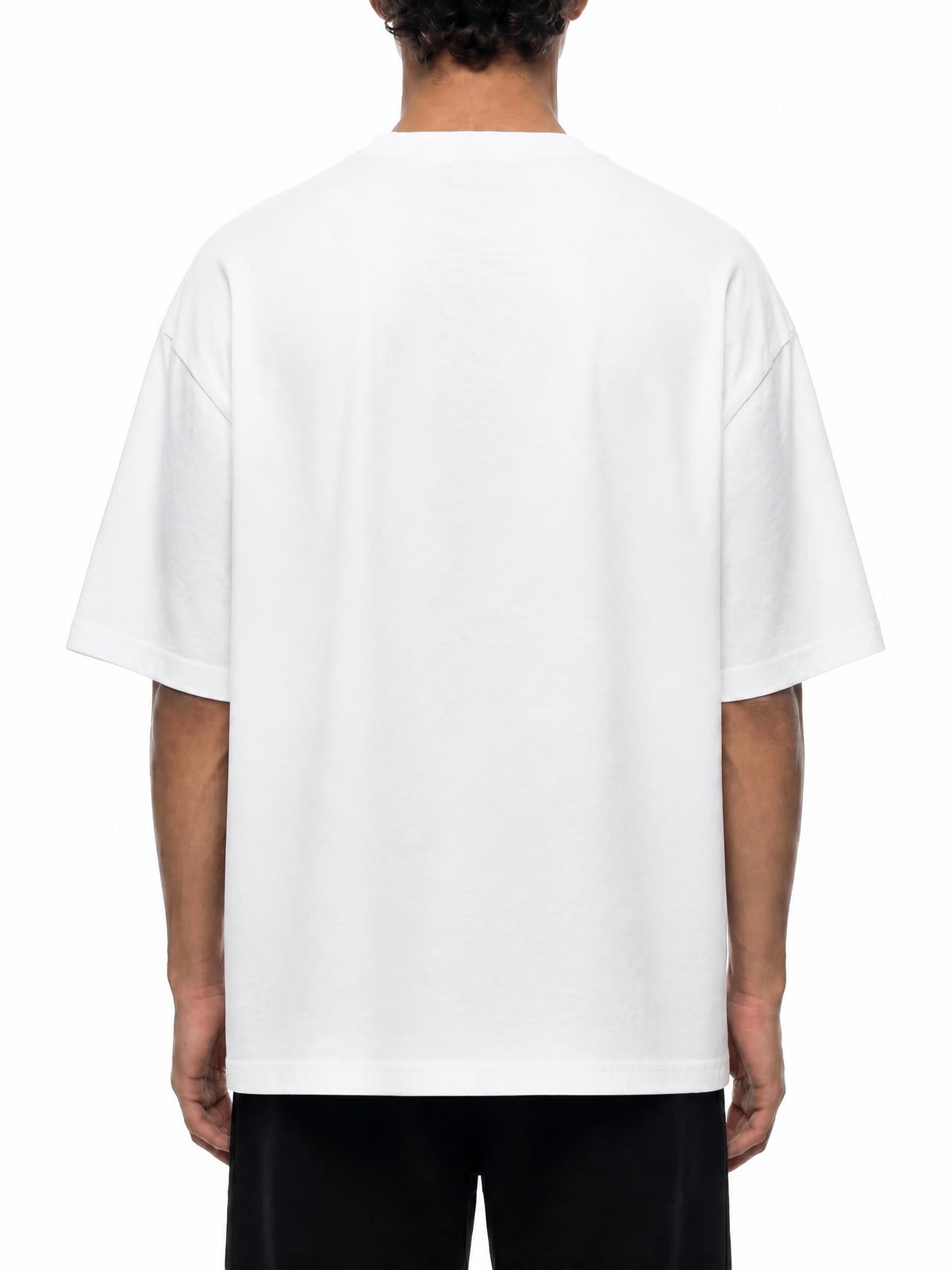 A person viewed from the back wearing an oversized white short-sleeve T-shirt and black pants against a plain white studio background.