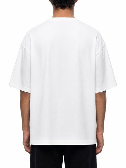 A person viewed from the back wearing an oversized white short-sleeve T-shirt and black pants against a plain white studio background.